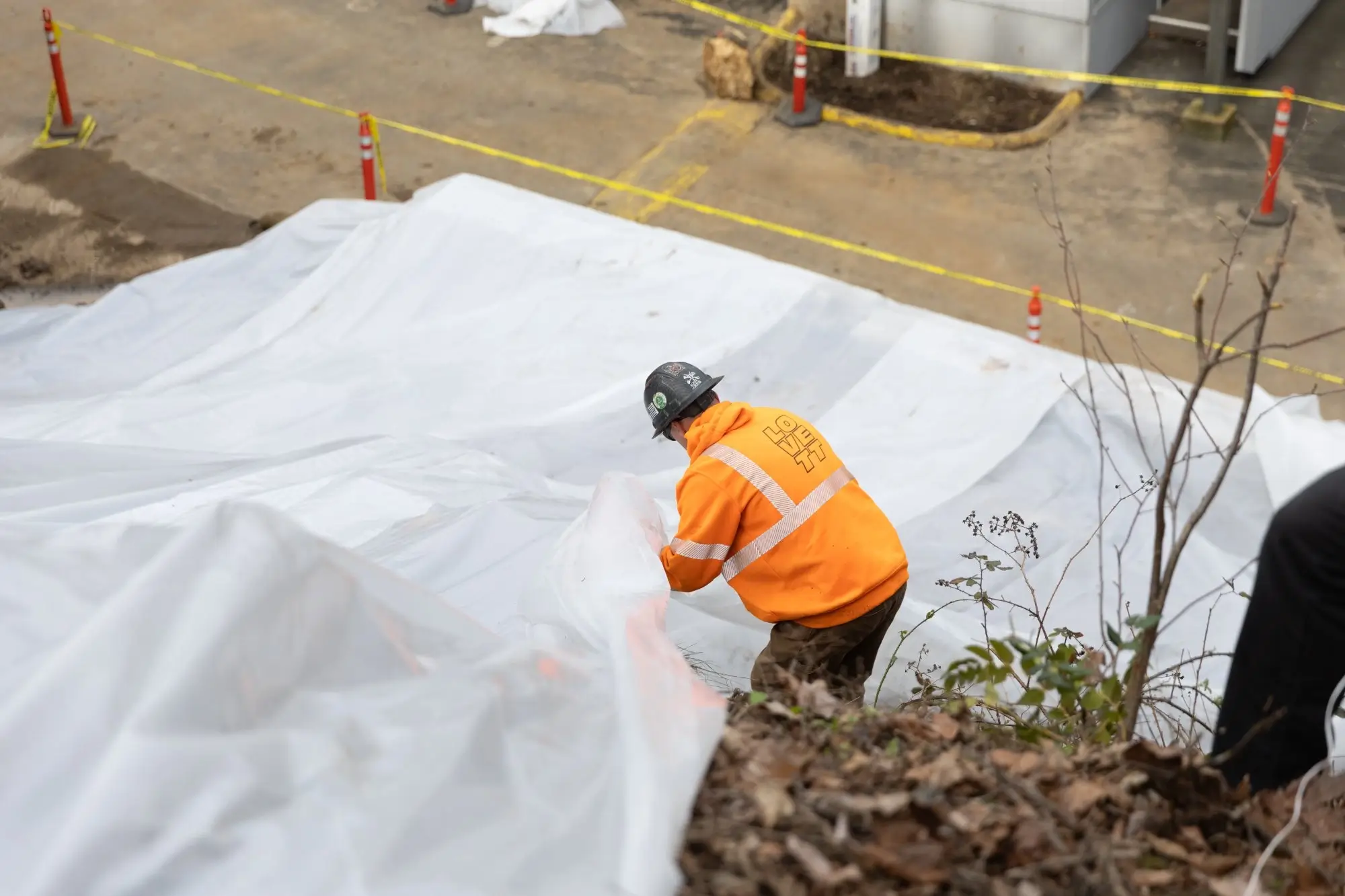 A crew member working the steep face of the slope to lock down tarping against future rainfall. This is what "leaving the site better than we found it" actually requires.