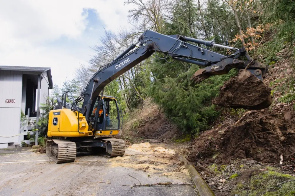 Excavator clearing debris from access road