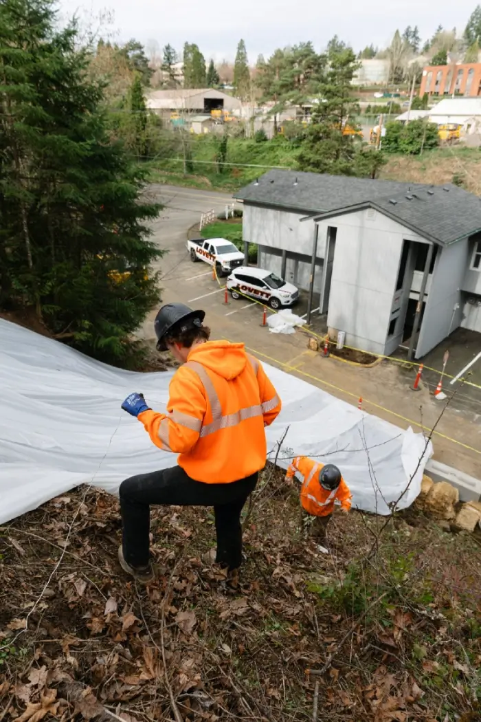 Crew securing tarping on the slope